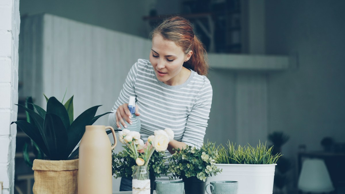 Woman caring for plants on a sunlit balcony